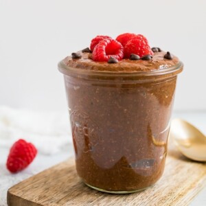 Chocolate chia pudding in a jar, topped with raspberries and mini chocolate chips.