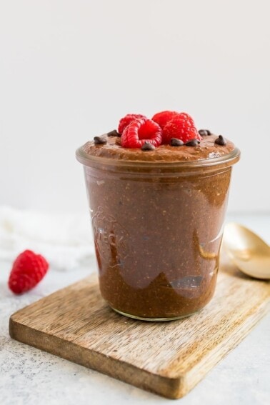 Chocolate chia pudding in a jar, topped with raspberries and mini chocolate chips.