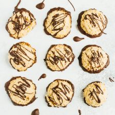 A tray of nine macaroons drizzled with dark chocolate, viewed from above..