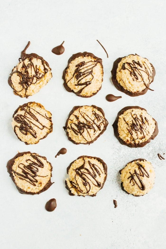 A tray of nine macaroons drizzled with dark chocolate, viewed from above.