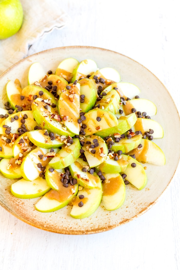 Sliced apples piled high with date caramel, chocolate chips, and nuts.