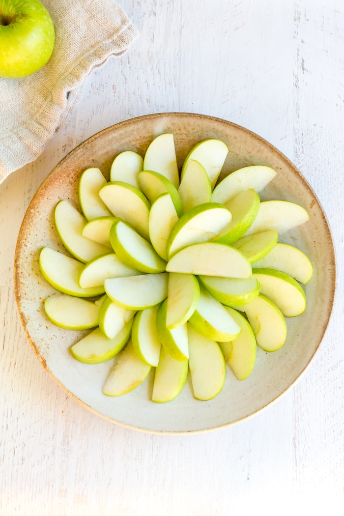 Building the base for the apple nachos with slices green apples.