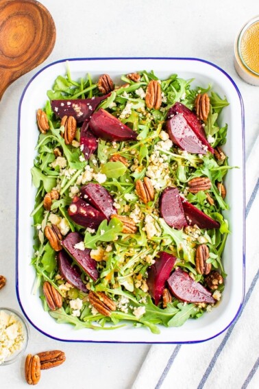 Regtangle serving tray and wooden spoon with arugula and beet salad topped with pecans and gorgonzola cheese.