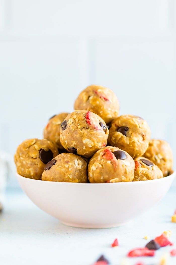 Bowl of peanut butter and jelly protein bites made with oats, dried strawberries, and chocolate chips.