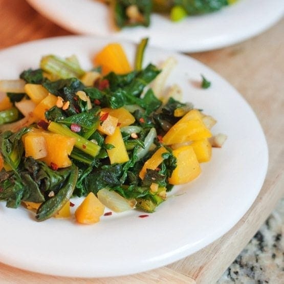 A close up of golden beet greens on a white plate.