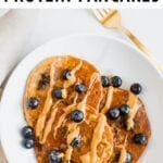 Blueberry protein pancakes on a plate drizzled with peanut butter.