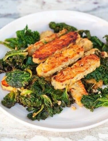 Lemon garlic tempeh slices over a bed of cooked kale.