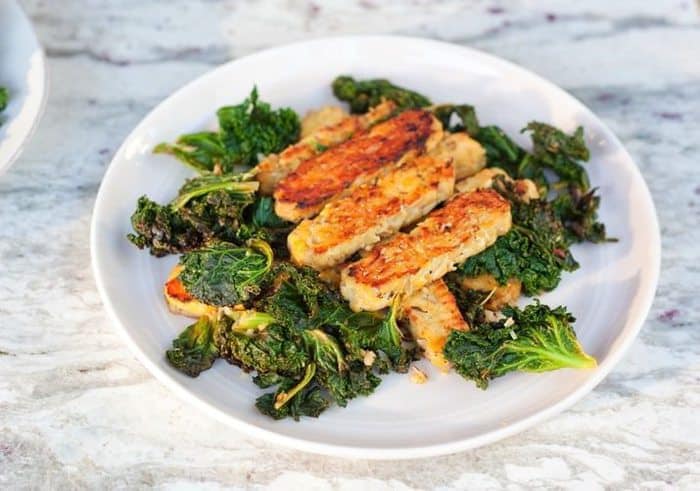 Lemon garlic tempeh slices over a bed of cooked kale. 