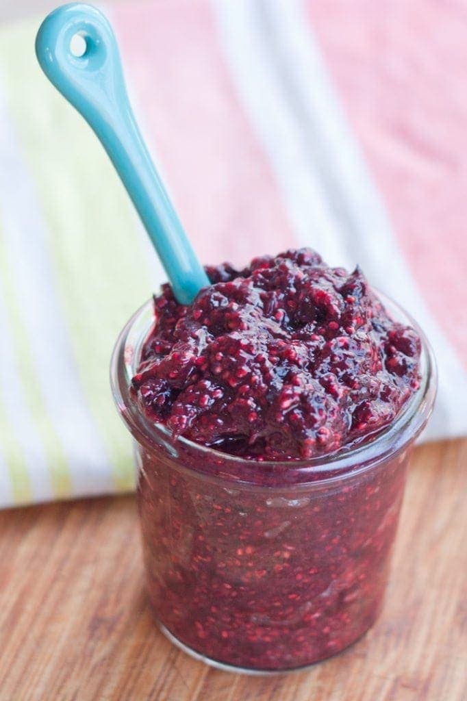 Mixed Berry Chia Seed Jam served in a small clear glass jar with light blue serving spoon.