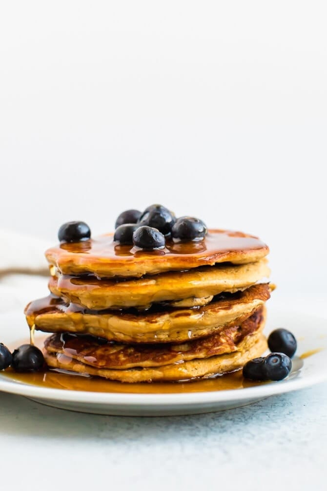 Stack of blueberry protein pancakes drizzled with maple syrup.