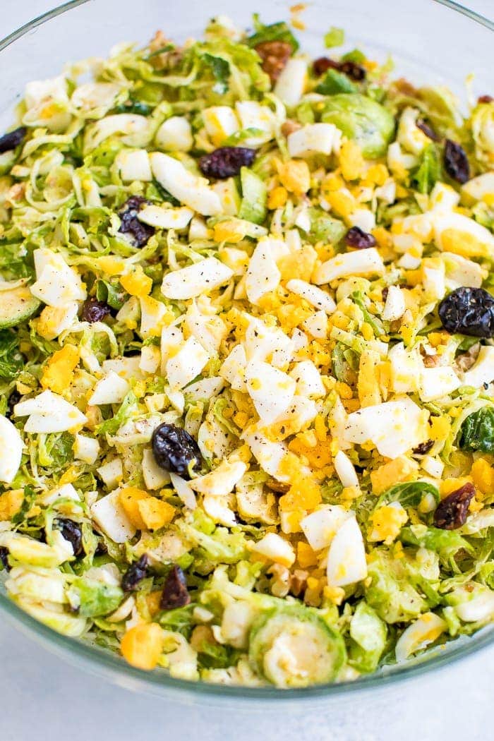 Healthy chopped Brussels sprout salad with feta, walnuts, cranberries, and egg.