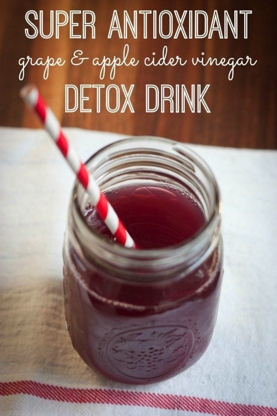 Mason jar with a purple liquid and a white and red striped straw sitting on a white towel. 