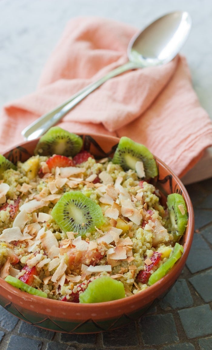 A bowl of quinoa fruit salad topped with toasted coconut and kiwi.