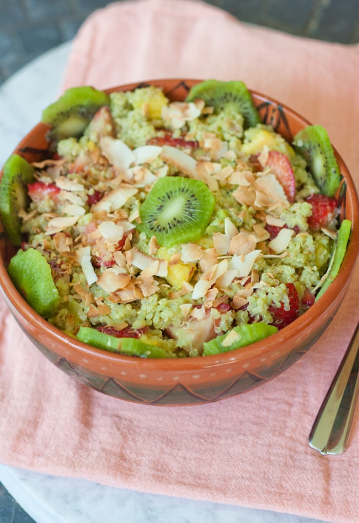 A bowl of quinoa fruit salad topped with toasted coconut and kiwi.