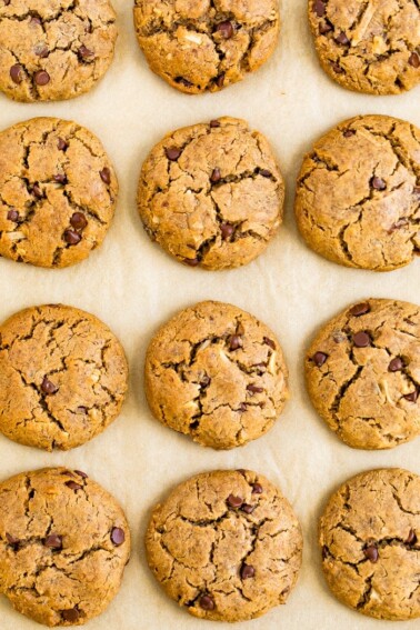 Chocolate chip tahini cookies on a baking sheet lined with parchment paper.