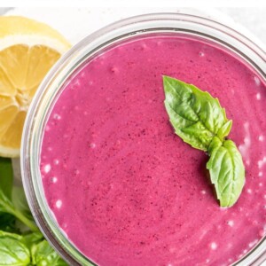 Glass jar with blueberry basil smoothie. Smoothie garnished with basil leaves.