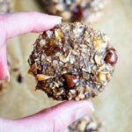 Hand holding an oatmeal chia cookies with flecks of coconut and chocolate chips.