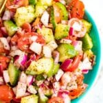 Cucumber tomato and onion salad in a blue and white bowl.