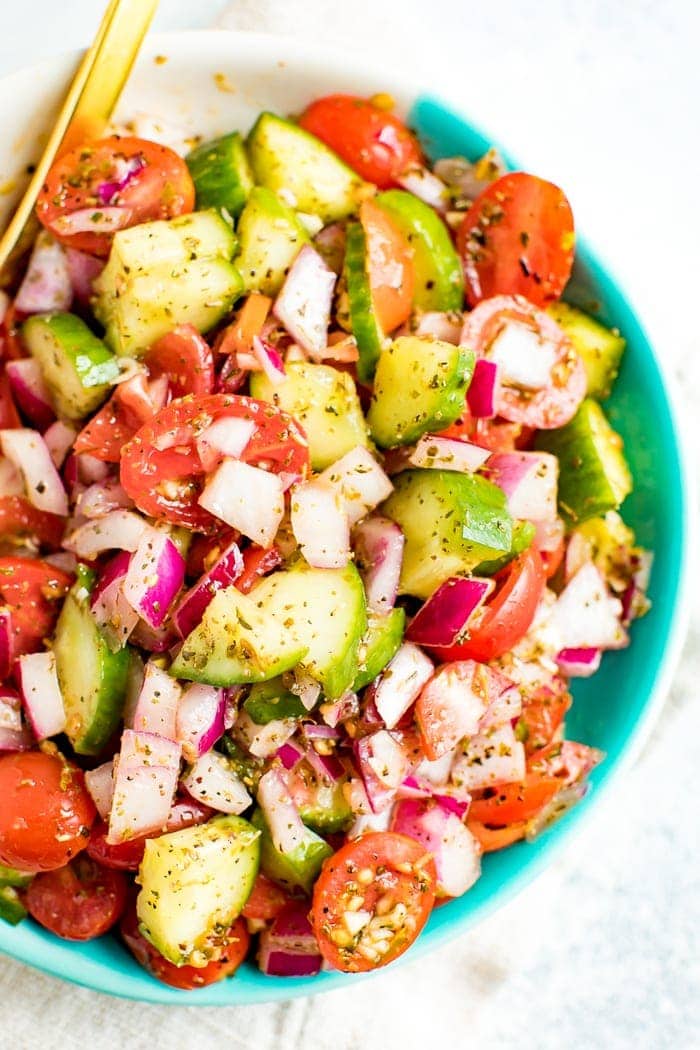 Cucumber tomato and onion salad in a blue and white bowl. 