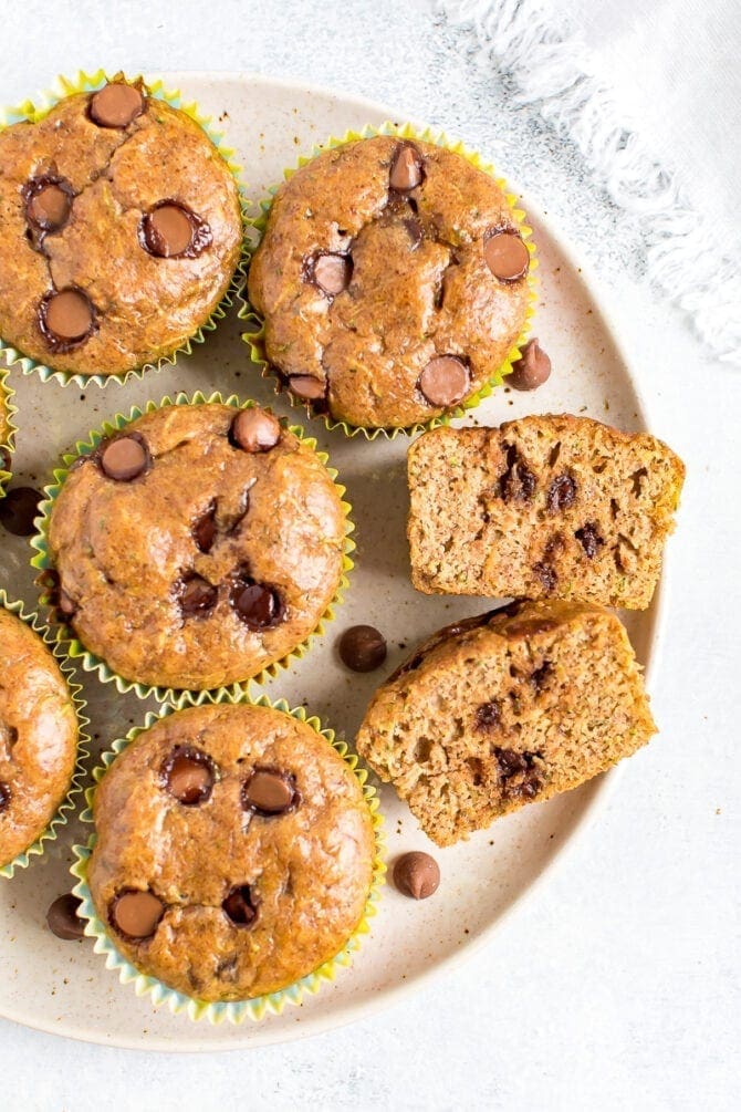 Plate of muffins. One muffin is sliced in half and you can see the chocolate chips.