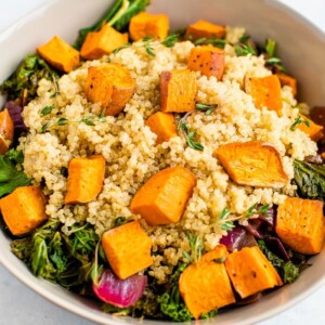 Kale salad with quinoa and roasted sweet potatoes on top.