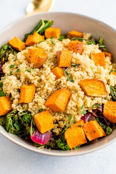 Kale salad with quinoa and roasted sweet potatoes on top.