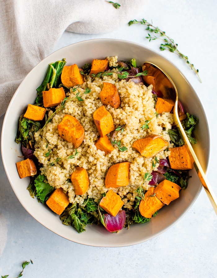 Salad bowl with kale, quinoa and roasted sweet potatoes topped wit fresh thyme.