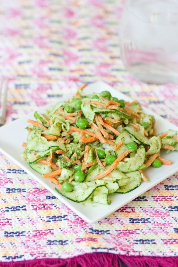 A plate of carrot and zucchini noodle pappardelle with pesto with a fork.