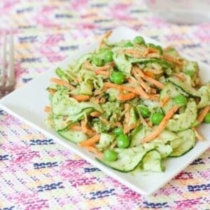 A plate of carrot and zucchini noodle pappardelle with pesto with a fork.