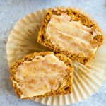 Healthy pumpkin cornbread muffin sliced and laying on a muffin liner and spread with ghee.