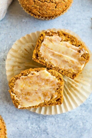 Healthy pumpkin cornbread muffin sliced and laying on a muffin liner and spread with ghee.