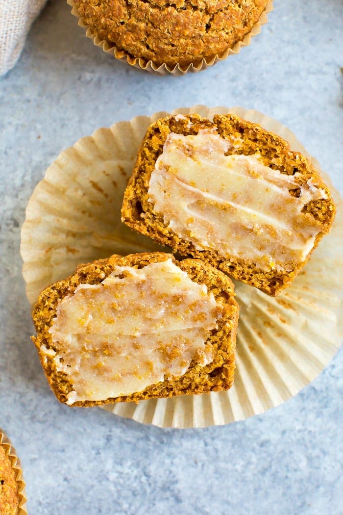 Healthy pumpkin cornbread muffin sliced in hand and laying on a muffin liner and spread with ghee.