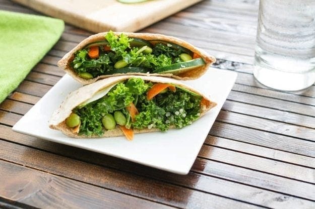 Kale Salad Stuffed Pitas served on a white square plate on wood table.