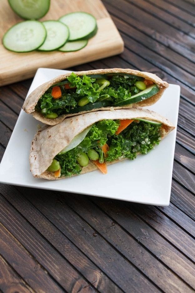 Kale Salad Stuffed Pitas served on a white square plate on wood table.