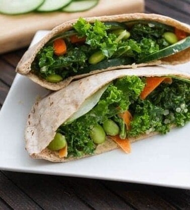 Kale Salad Stuffed Pitas served on a white square plate on wood table.