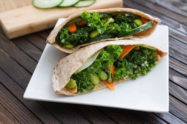 Kale Salad Stuffed Pitas served on a white square plate on wood table.