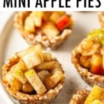 Mini raw apple pies on a plate. A napkin and apple slices are also on the table.