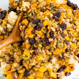 Bowl and wooden spoon with quinoa stuffing made with cranberries and butternut squash.