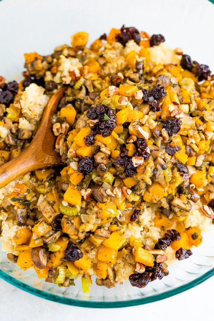 Bowl and wooden spoon with quinoa stuffing made with cranberries and butternut squash.
