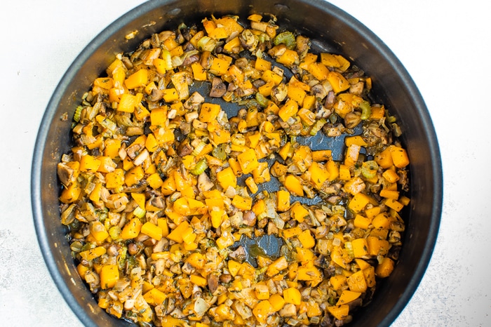 Celery and butternut squash being sauteed in a pan.