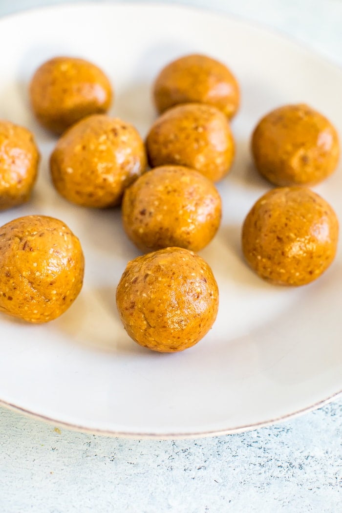 Healthy peanut butter balls on a plate before getting dipped in chocolate.