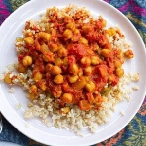 Channa Masala served with brown rice on white plate and colorful placemat.