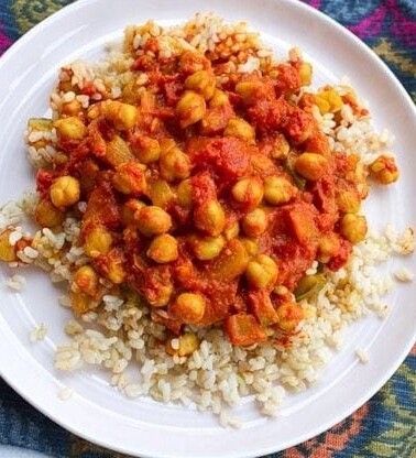 Channa Masala served with brown rice on white plate and colorful placemat.