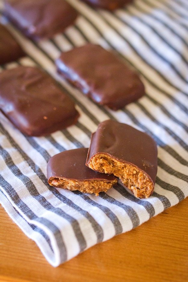 A homemade chunky almond butter thinkthin bar split in half, resting on a striped dish cloth.