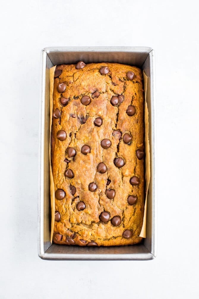 Loaf pan with chocolate chip coconut flour banana bread topped with chocolate chips.