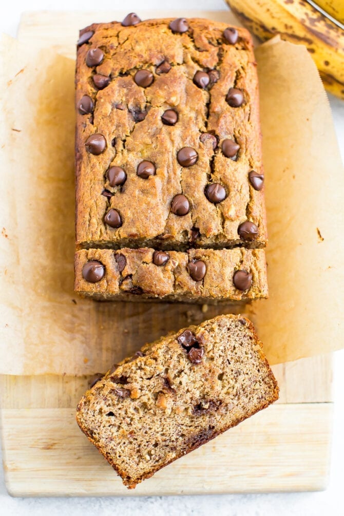 Loaf of chocolate chip coconut flour banana bread with a couple slices on a cutting board.