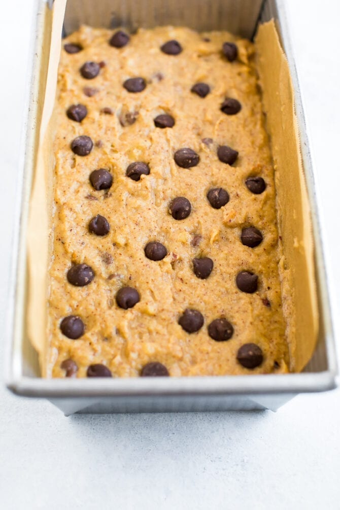 Unbaked batter for chocolate chip coconut flour banana bread in a loaf pan topped with extra chocolate chips.