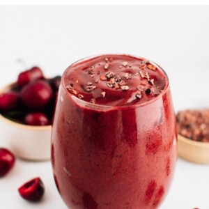 Chocolate cherry smoothie in a glass and topped with cacao nibs.