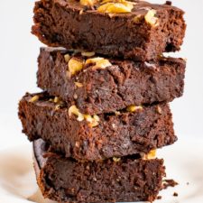 Stack of flourless back bean brownies, topped with chocolate chips and walnuts.