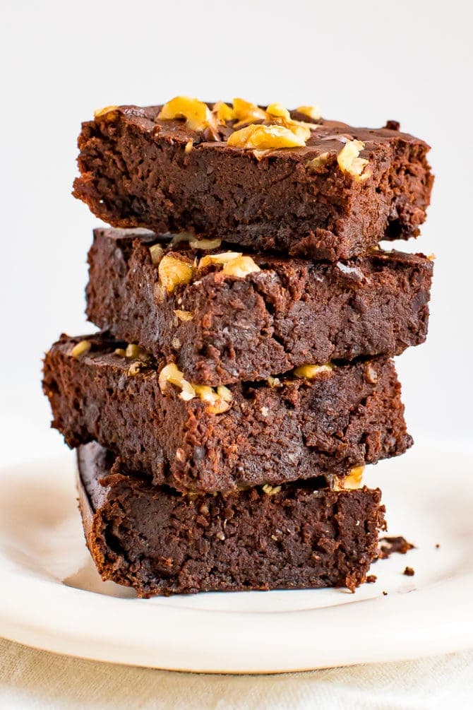 Stack of flourless back bean brownies, topped with chocolate chips and walnuts.